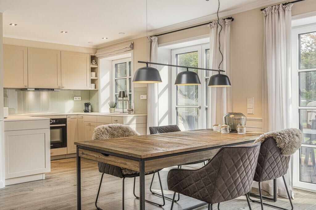 Cozinha moderna com mesa de jantar de madeira, luminárias pendentes pretas e vista para o exterior através de grandes janelas.