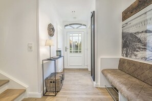 A hallway with a bench, a lamp, and a door leading to another room. - Holiday home in St. Peter-Ording with sauna (St.Peter-Ording)