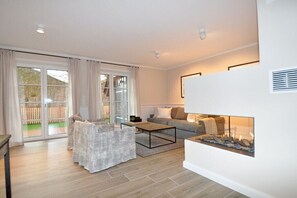 A modern living room with a sofa, armchairs, a coffee table, and a fireplace. - Holiday home in St. Peter-Ording with sauna (St.Peter-Ording)