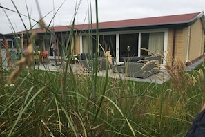 Een woongebouw met een rood dak, grote ramen en een patio met buitenmeubilair.