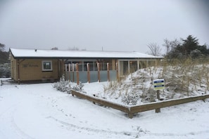 Een gebouw met een overdekt terras, een bord dat een plaats aangeeft, en een met sneeuw bedekte grond.