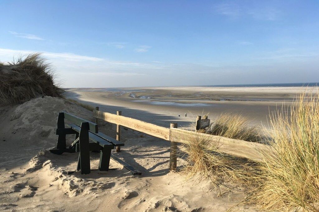 Une plage de sable avec une clôture en bois et un banc.