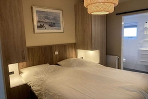 Een slaapkamer met een bed, een aan de muur hangend schilderij en een hanglamp.