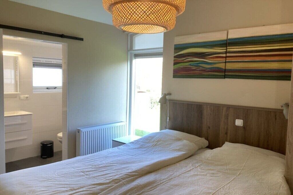Una camera da letto con un letto, una finestra, un termosifone e un quadro appeso al muro.