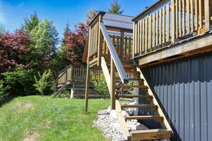 A wooden deck with a staircase leading to a metal roofed structure.