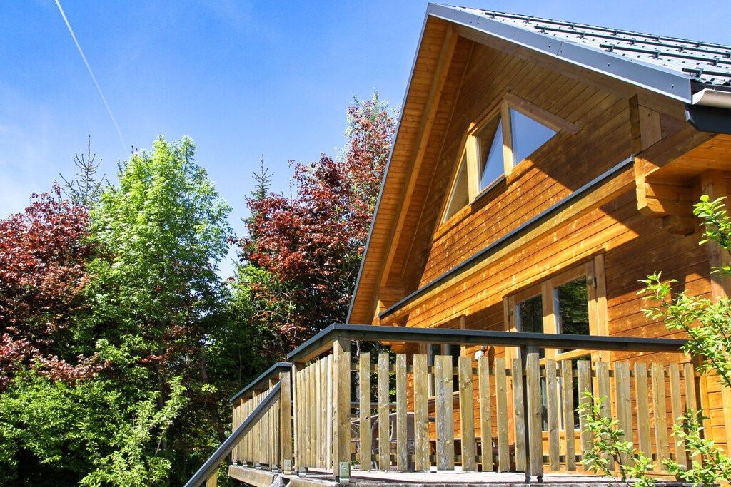 A wooden cabin with a balcony and a sloped roof.