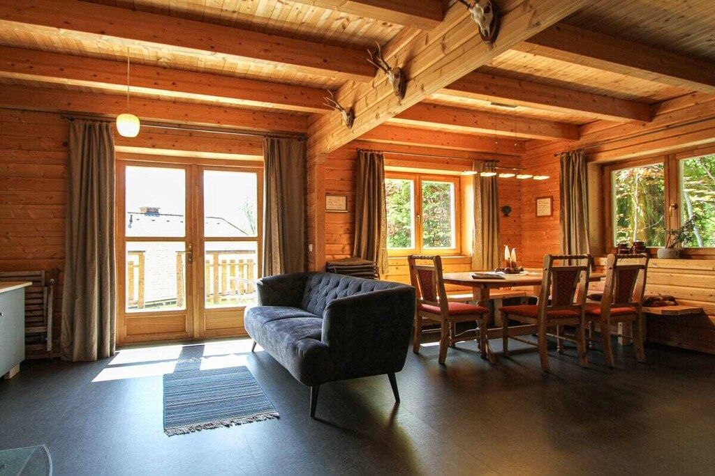 L'intérieur d'un chalet en bois, avec un canapé, une table à manger, des chaises et une cheminée.