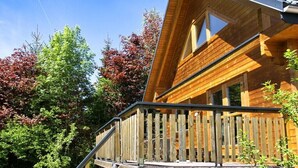 A wooden cabin with a sloped roof, a balcony, and a window.
