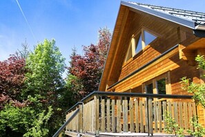 A wooden cabin with a sloped roof, a balcony, and a window.