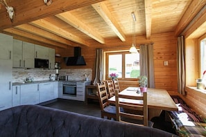 A wooden cabin interior with a kitchen, dining area, and a sofa. - Cabin with 3 bedrooms (Bad Mitterndorf)
