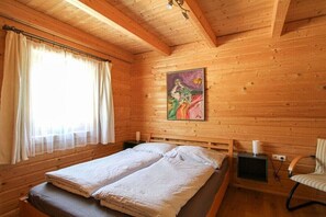 A wooden cabin room with a bed, a chair, and a painting on the wall. - Cabin with 3 bedrooms (Bad Mitterndorf)