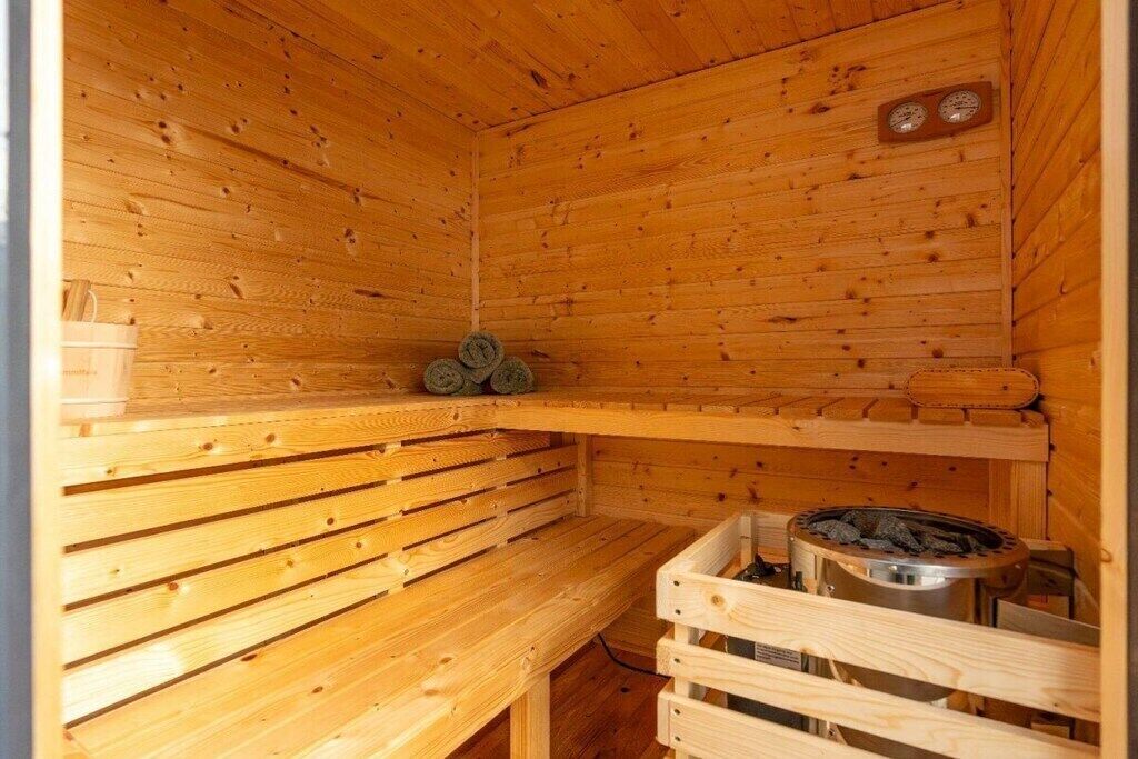 A wooden sauna with benches and a sauna heater.