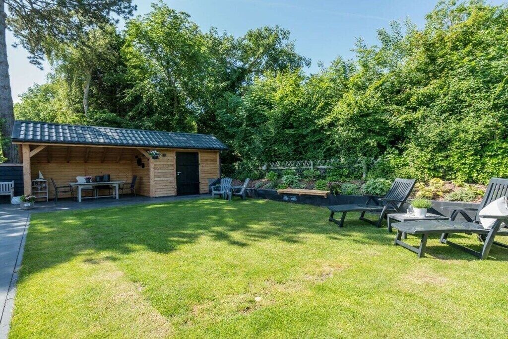 A wooden cabin with a tiled roof, a patio with outdoor furniture, and a well-maintained lawn.