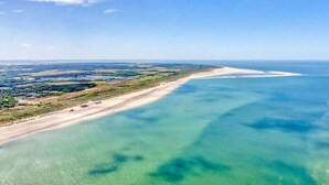 Eine Küstenlandschaft mit sandigem Strand und klarem, blauem Wasser.