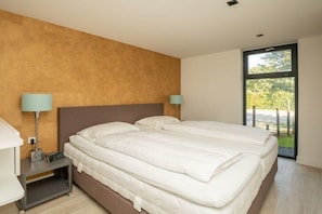 A hotel room with a large bed, bedside tables, and a window with a view. - Holiday home in Renesse with swimming pool (Renesse)