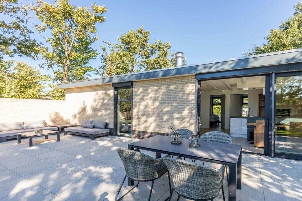 Eine Terrasse im Freien mit Esstisch und Stühlen, einer Couch und einer Ziegelwand.