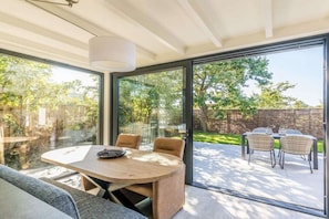 A modern interior with a glass door leading to an outdoor patio area. - Holiday home in Renesse with swimming pool (Renesse)