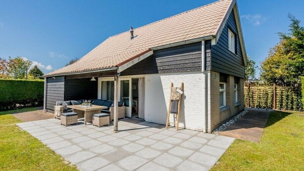 Ein zweistöckiges Haus mit überdachter Terrasse, Essbereich und Garage.