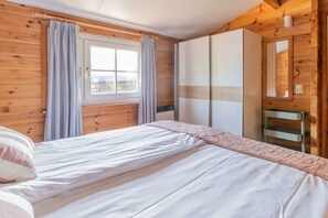 A bedroom with a bed, a wardrobe, and a window with curtains. - Holiday home in Renesse with swimming pool (Renesse)