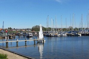 A marina with multiple boats docked, a sailboat in the foreground, and a clear sky. - Holiday home with 1 bedroom (Ostseebad Rerik)