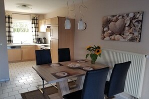 A dining area with a wooden table, black chairs, and a vase with sunflowers. - Holiday home with 1 bedroom (Ostseebad Rerik)