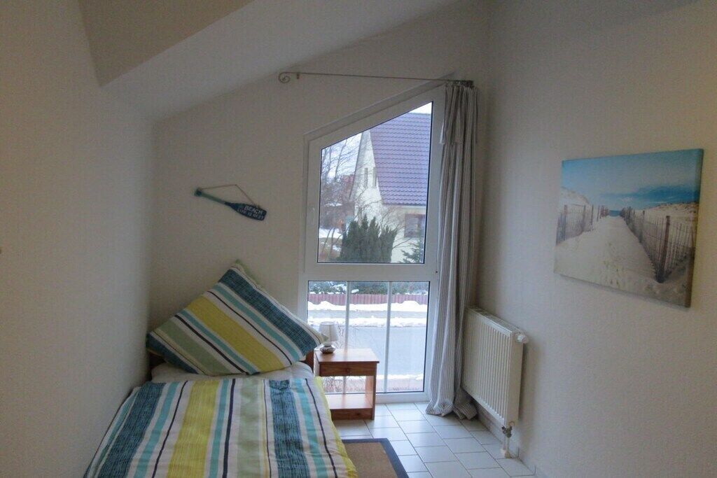 A bedroom with a bed, a window, a radiator, and a painting on the wall.
