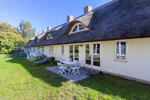 A house with a thatched roof, white exterior walls, and a patio with outdoor furniture. - Green Cottage by the Swan Pond (Lassan)