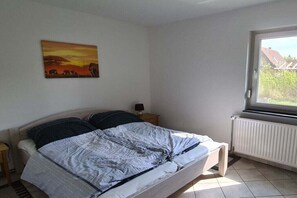 A bedroom with a bed, a nightstand, a window, and a painting on the wall. - Bungalow in Priepert with swimming pool (Priepert)