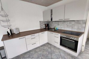 A compact kitchen with white cabinets, a wooden countertop, a built-in oven, and a hanging light fixture. - Bungalow in Priepert with swimming pool (Priepert)