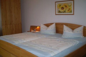 Ein Bett mit Holzgestell, zwei Kissen und ein Nachttisch mit Lampe.