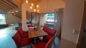 A modern dining area with a wooden table and red upholstered chairs, a glass partition, and a view of the outside.