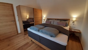 Ein Schlafzimmer mit Bett, Nachttischen, einem Kleiderschrank und einer Tür.