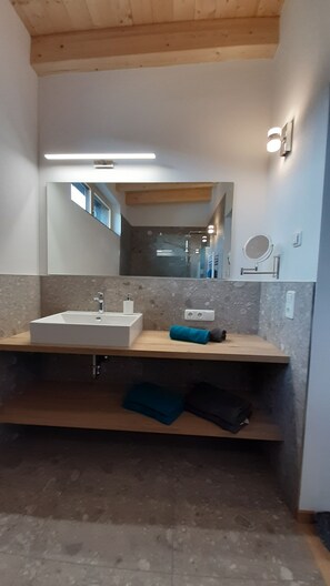 A modern bathroom with a large mirror, two sinks, and a towel rack.