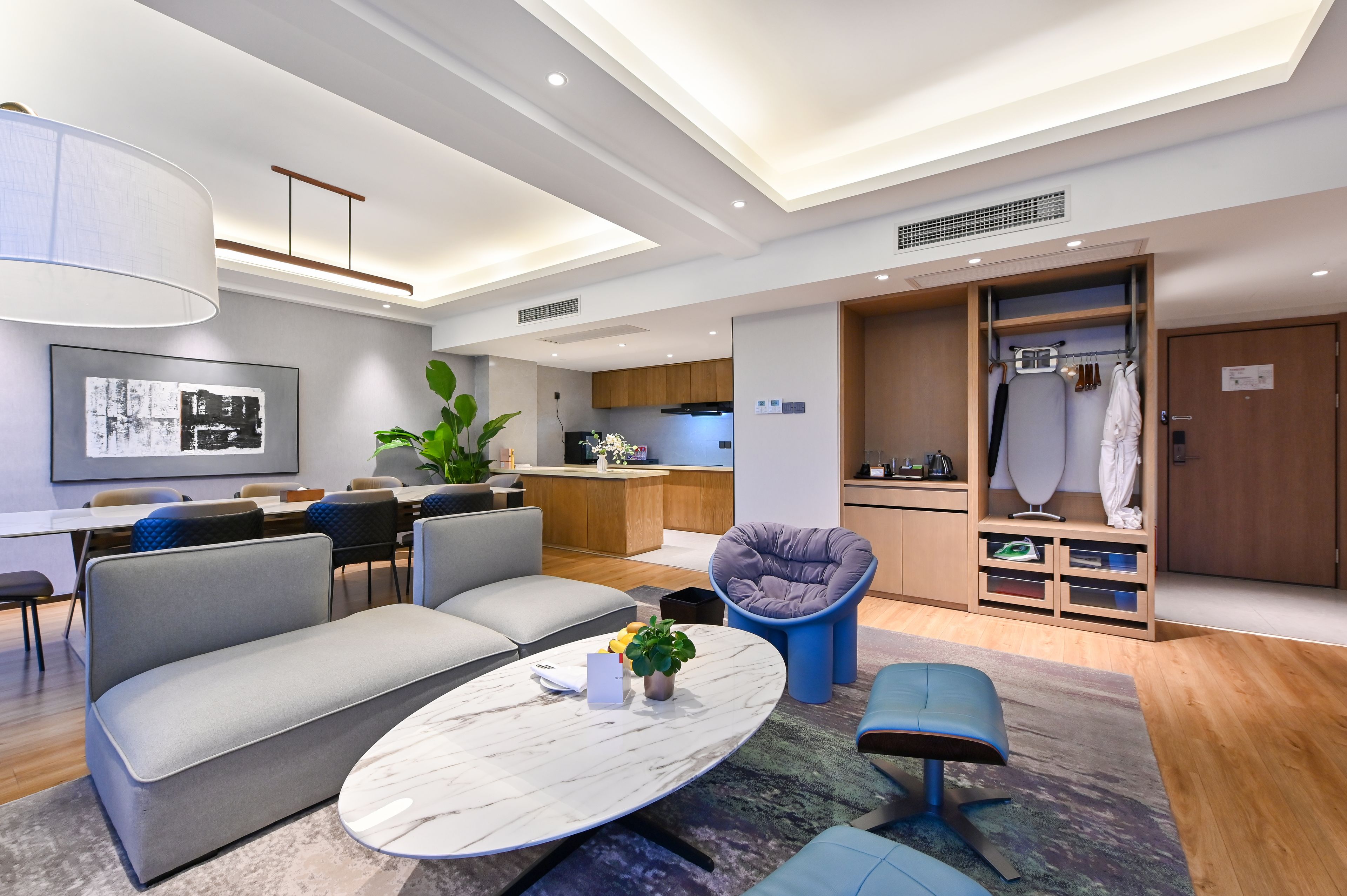 Una sala de estar moderna con un sofá, una mesita redonda y un rincón de asiento con una silla acolchada.