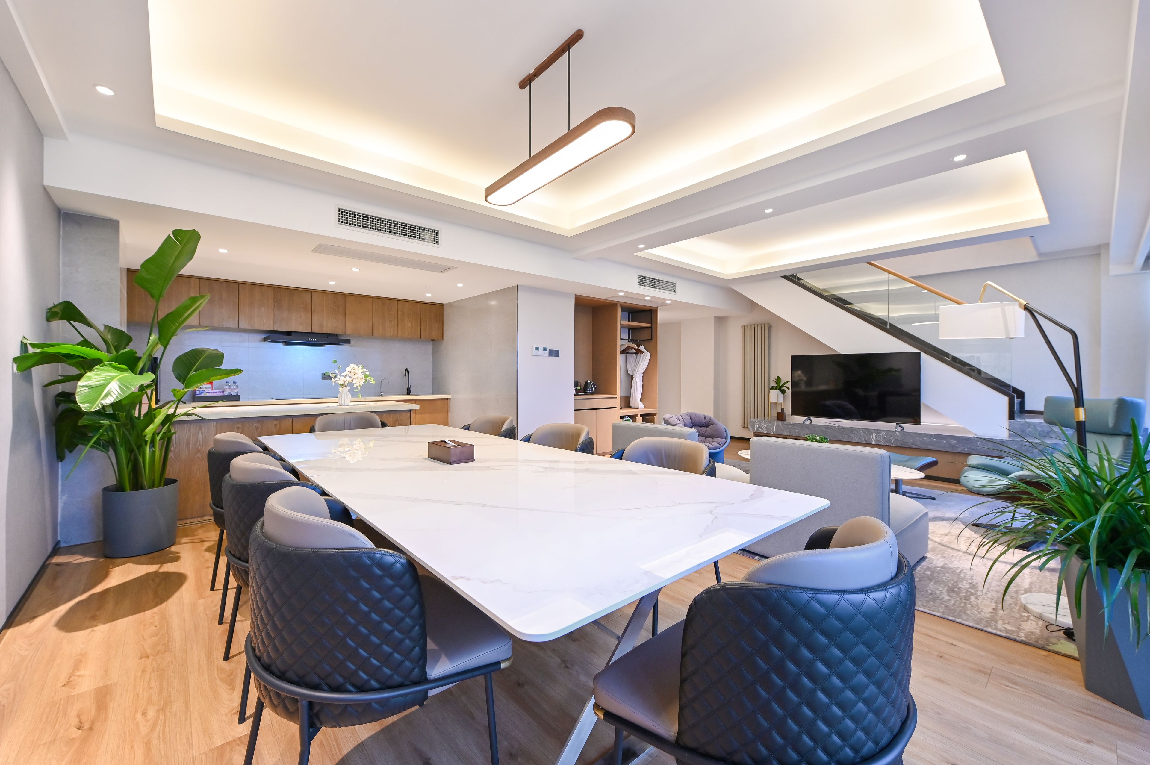 A modern living space with a dining area, kitchen, and a staircase leading to an upper level.