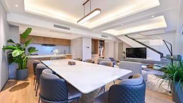 A modern living space with a dining area, kitchen, and a staircase leading to an upper level.