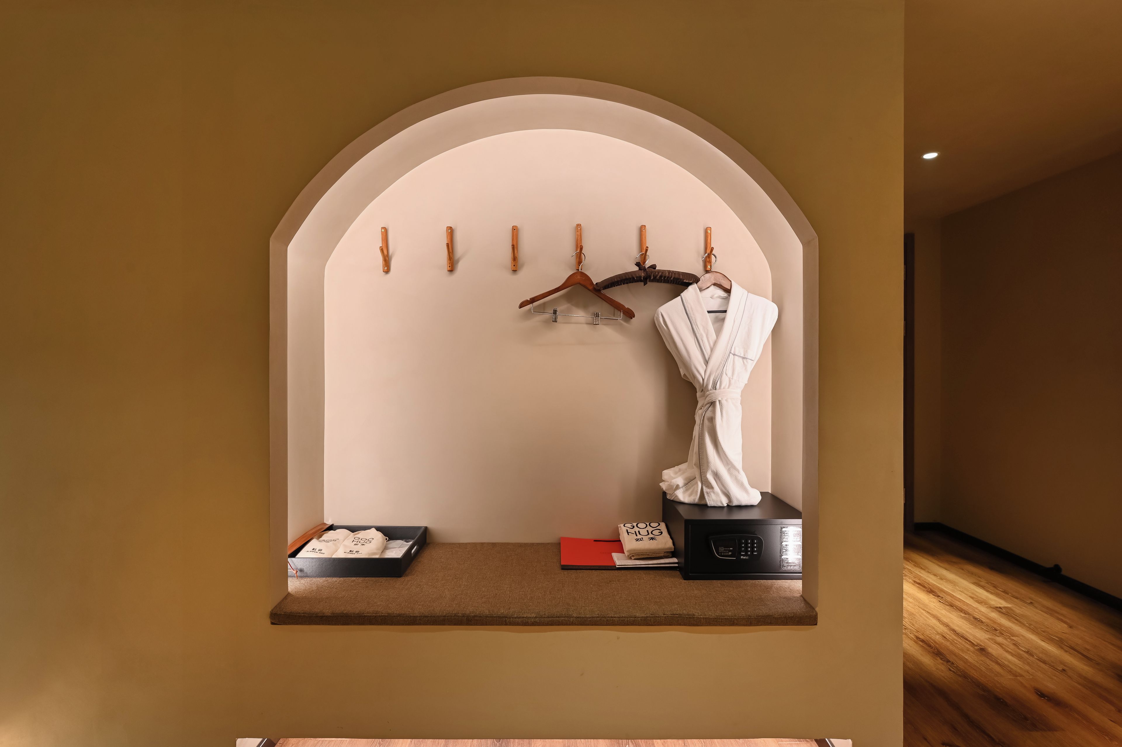 Habitación con estante incorporado que contiene una bata, una bandeja con toallas y un electrodoméstico negro.