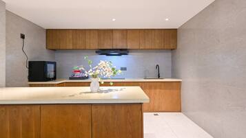A modern kitchen with wooden cabinets, a built-in microwave, and a vase with flowers on the counter.