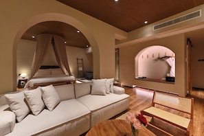 A bedroom with a canopy bed, a sofa, a rattan chair, and a window with a view. - BEIJING GOOHUG HOTEL (Beijing)