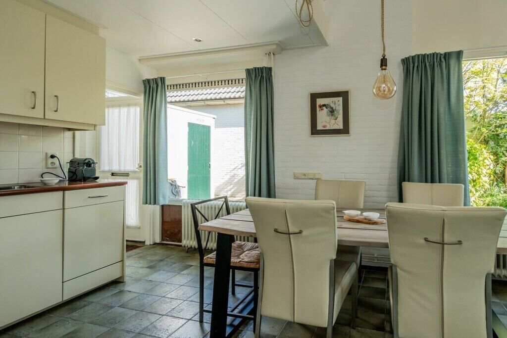 Une cuisine avec un coin repas, un radiateur et une fenêtre avec des rideaux.