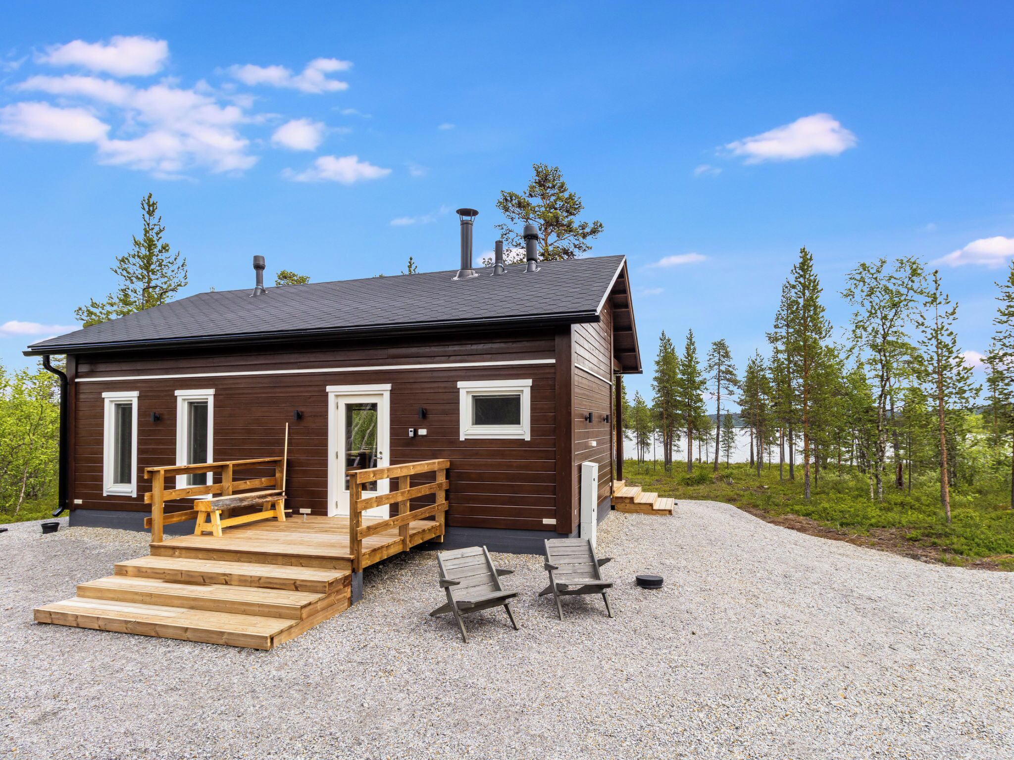 Eine Holzhütte mit einer Veranda und Holzstufen sowie einer Schotterauffahrt.