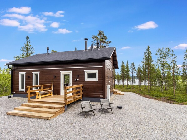 Eine Holzhütte mit einer Veranda und Holzstufen sowie einer Schotterauffahrt.