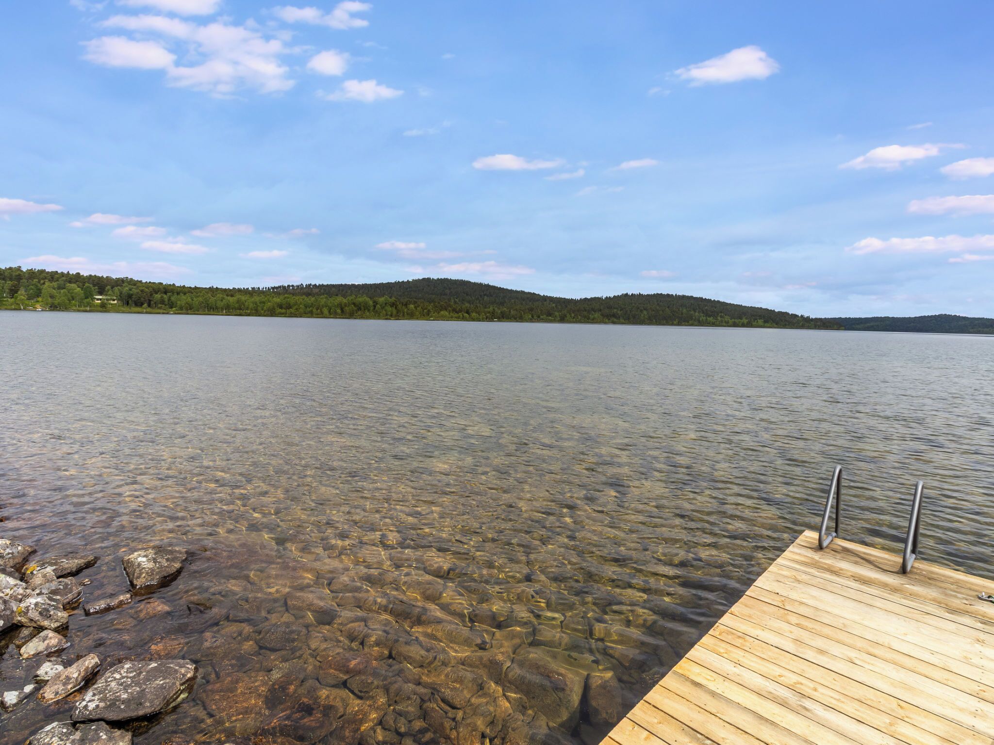 A clear lake with a wooden dock extending into the water.