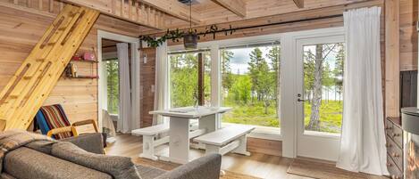 A cozy cabin interior with a loft bed, a dining area with benches, and a fireplace.