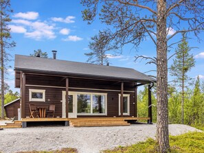 Eine Hütte mit überdachter Veranda, großen Fenstern und einem Schotterweg.