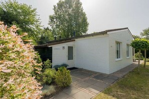 A single-story white building with a small porch, a door labeled 'Schule,' and a pathway leading to the entrance. - Holiday home in Renesse with swimming pool (Renesse)