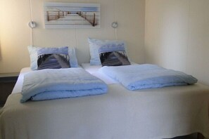 A double bed with two pillows, a wall-mounted picture, and a bedside table. - Holiday apartment with 2 bedrooms (Callantsoog)