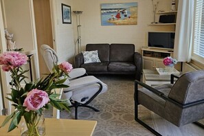 A living room with a sofa, armchairs, a coffee table, and a painting on the wall. - Holiday apartment with 2 bedrooms (Callantsoog)