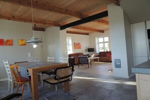 Ein geräumiger Wohnbereich mit Holzboden, einem Esstisch mit Stühlen, einer Couch und einem Fernseher.