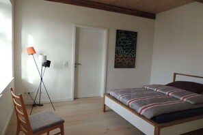 Une chambre à coucher avec un lit, une chaise, une lampe sur pied et une porte.